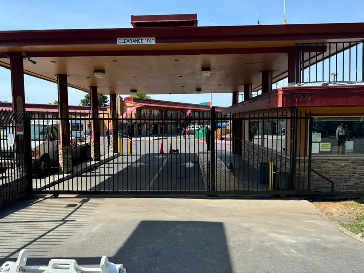Motel entrance wide shot with closed black ornamental iron slide gate