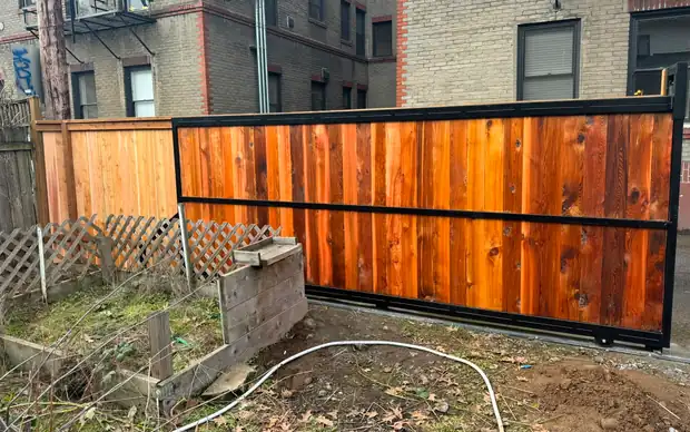 Wide view of cedar slide gate in black frame beside lattice and cedar fence — Interstate Gate Repair