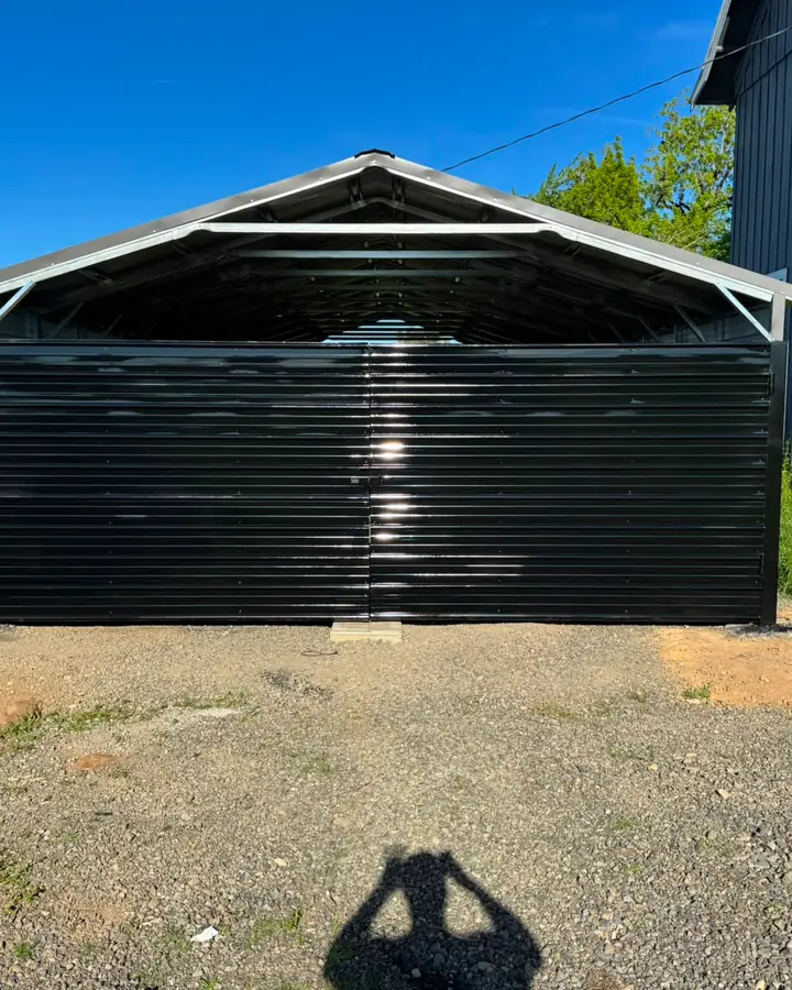 Black metal double swing gate on steel carport, exterior, clear sky — Interstate Gate Repair